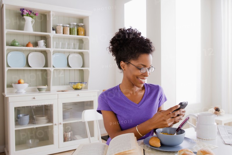 Young woman using mobile at breakfast. Photo : Rob Lewine