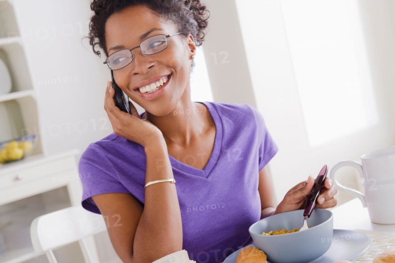 Young woman using mobile at breakfast. Photo : Rob Lewine