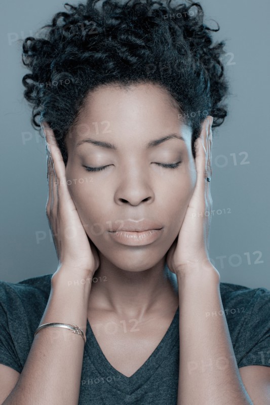 Studio shot of young woman with hands covering ears. Photo : Rob Lewine