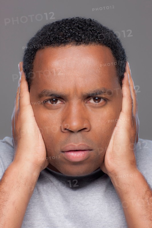 Studio shot of mid adult man covering ears. Photo : Rob Lewine