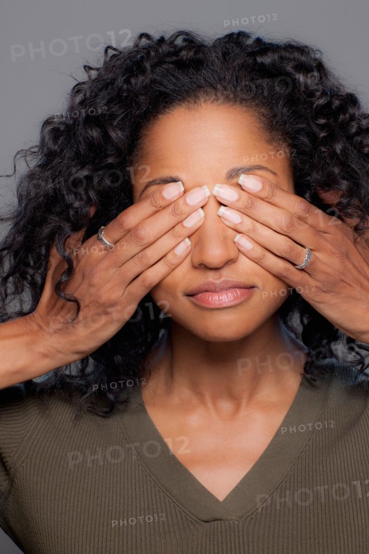 Studio shot of mid adult woman covering eyes. Photo : Rob Lewine