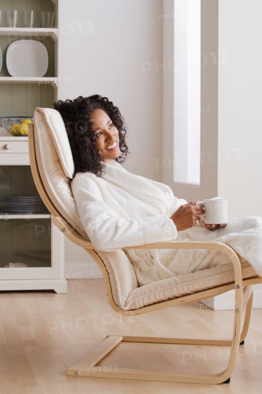 Woman drinking coffee in armchair in morning. Photo : Rob Lewine