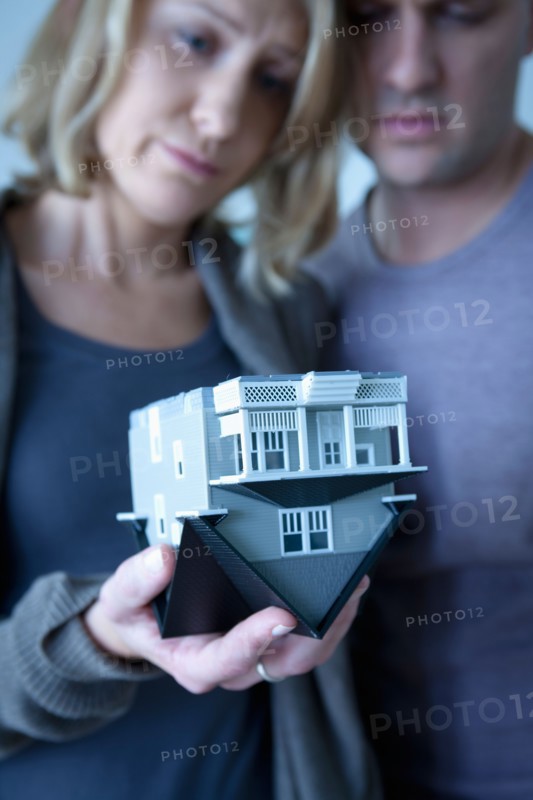 Mid adult couple holding wooden model of house. Photo : Rob Lewine
