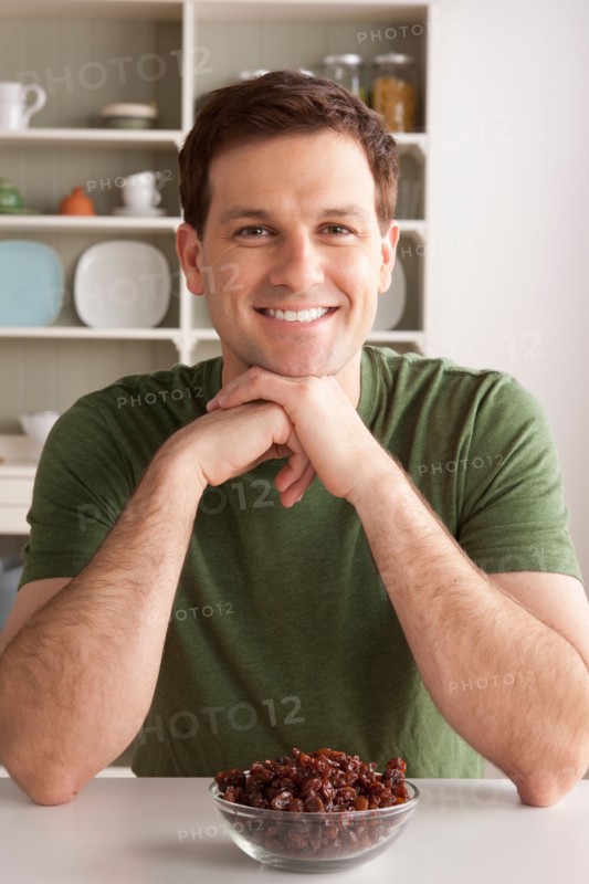 Portrait of mid adult man with bowl of raisins. Photo : Rob Lewine