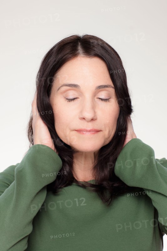 Studio portrait of mature woman covering ears. Photo : Rob Lewine