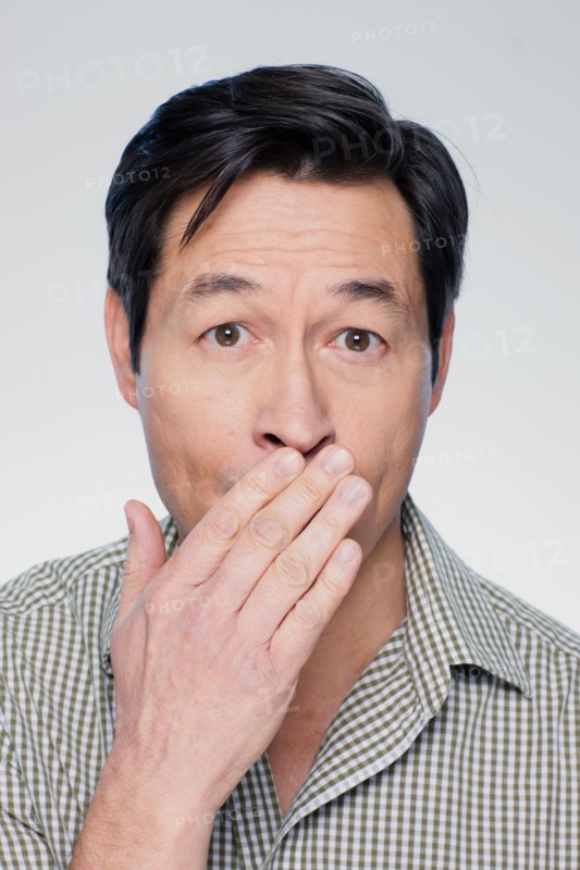 Studio portrait of mature man covering mouth. Photo : Rob Lewine