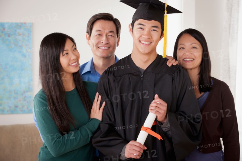 Portrait of young man in graduation gown with family. Photo : Rob Lewine