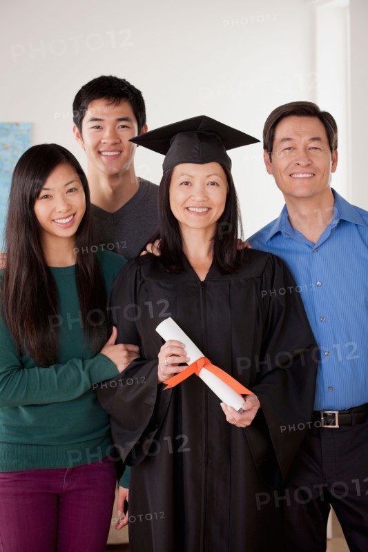 Portrait of mature woman in graduation gown with family. Photo : Rob Lewine