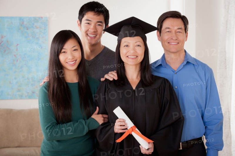 Portrait of young man in graduation gown with family. Photo : Rob Lewine