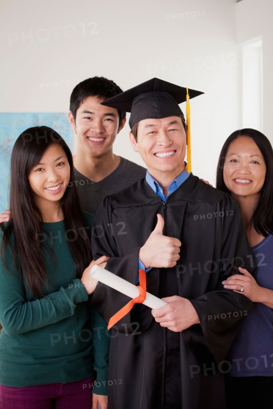 Portrait of mature man in graduation gown with family. Photo : Rob Lewine