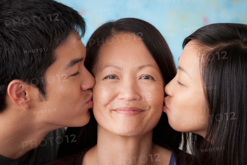 Smiling mother kissed by her children. Photo : Rob Lewine