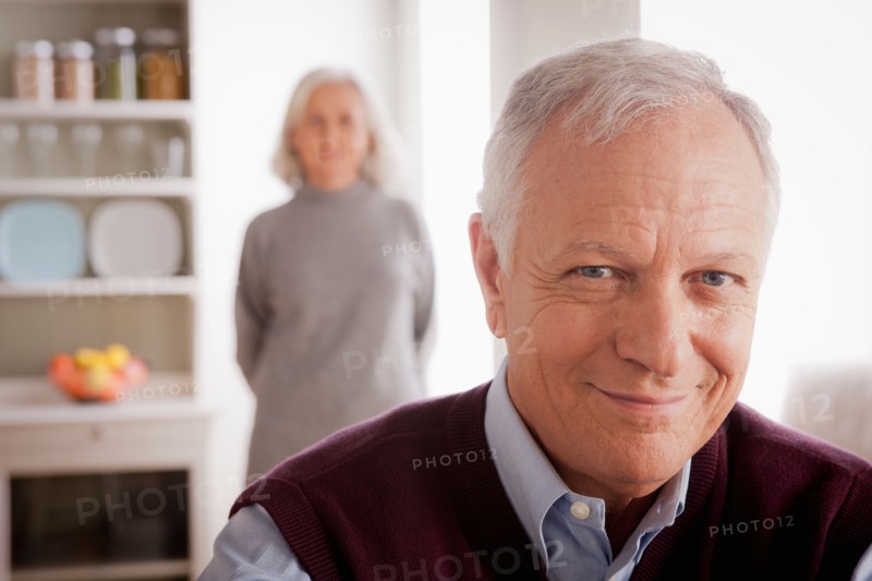 Portrait of smiling senior man, senior woman in background. Photo : Rob Lewine