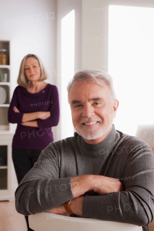 Portrait of smiling senior man, senior woman in background. Photo : Rob Lewine