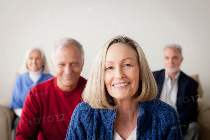 Two senior couples on sofa, smiling woman in foreground. Photo : Rob Lewine