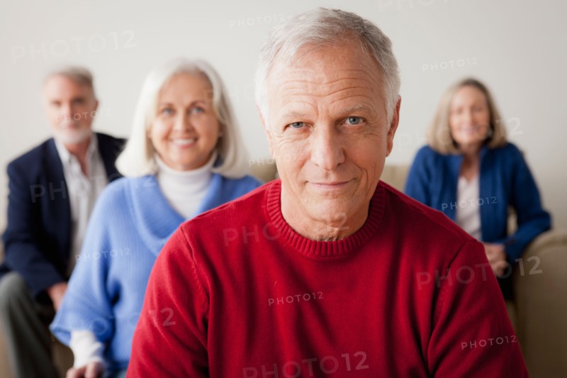 Two senior couples on sofa, smiling man in foreground. Photo : Rob Lewine
