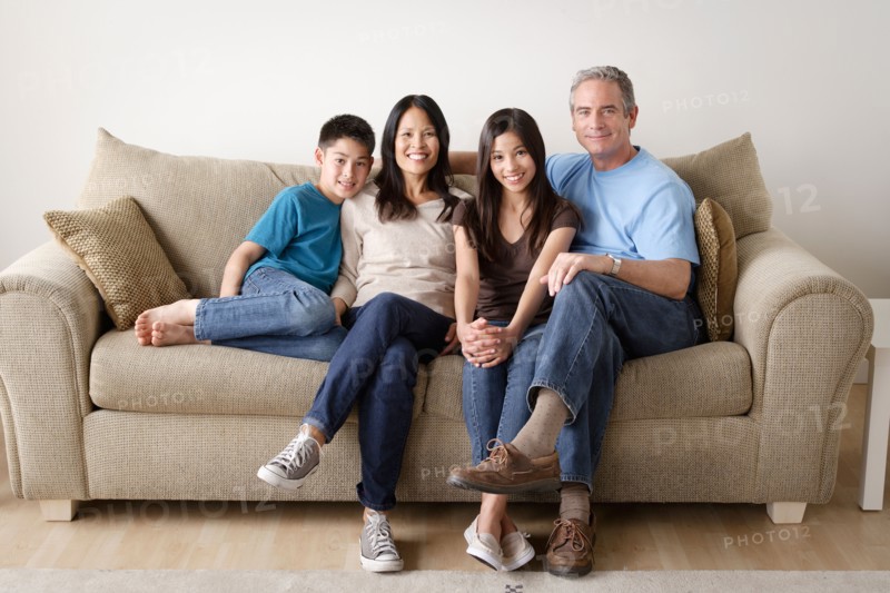 Cheerful family sitting on sofa. Photo : Rob Lewine