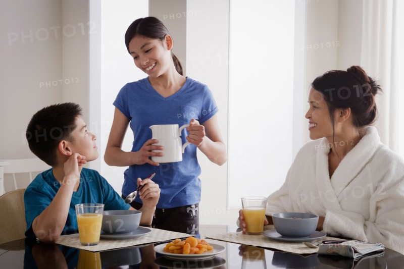 Girl serving milk to family over breakfast. Photo : Rob Lewine