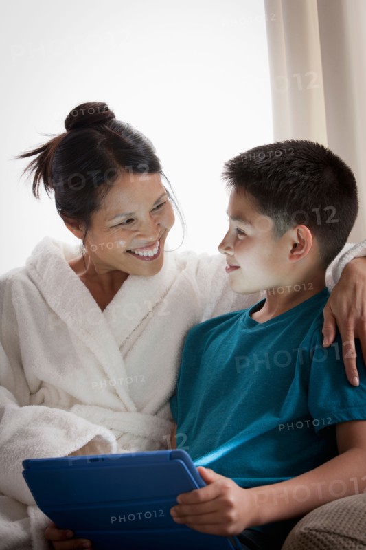 Mother embracing son using laptop. Photo : Rob Lewine