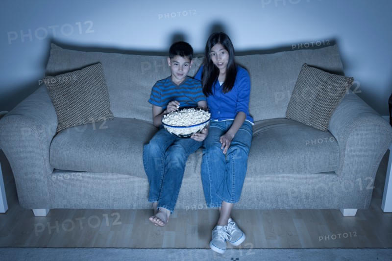 Brother and sister (10-11, 12-13) watching television. Photo : Rob Lewine