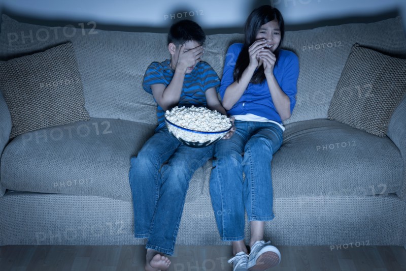 Brother and sister (10-11, 12-13) watching television. Photo : Rob Lewine