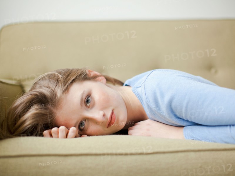 Indoor portrait of young attractive woman reclining on sofa. Photo : Jessica Peterson