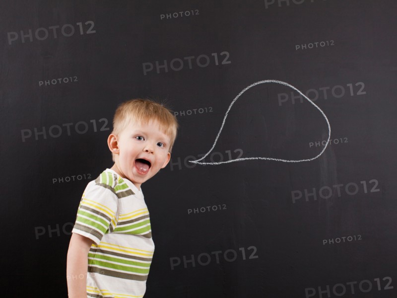 Studio portrait of happy toddler boy (2-3) with blank speech bubble written on blackboard. Photo : Jessica Peterson