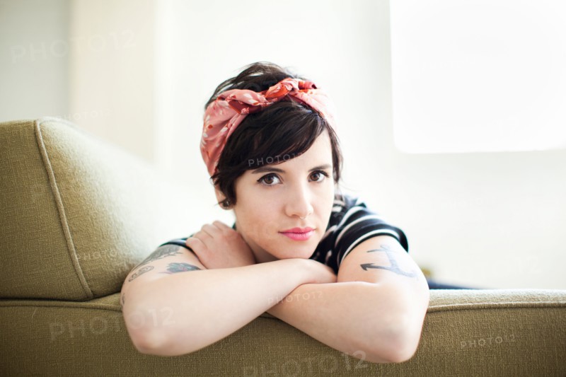 Young woman sitting on sofa. Photo : Jessica Peterson