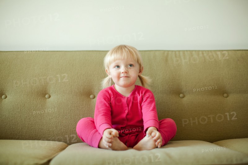 Portrait of baby girl (18-23 months) sitting on sofa. Photo : Jessica Peterson