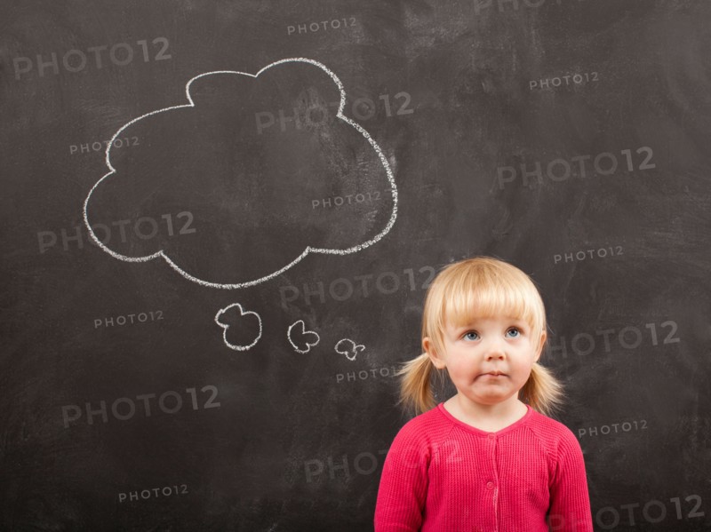 Portrait of baby girl (18-23 months) in front of blackboard. Photo : Jessica Peterson