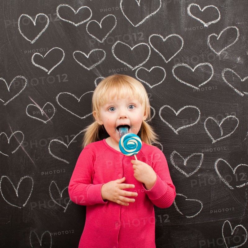 Portrait of baby girl (18-23 months) eating lollipop. Photo : Jessica Peterson