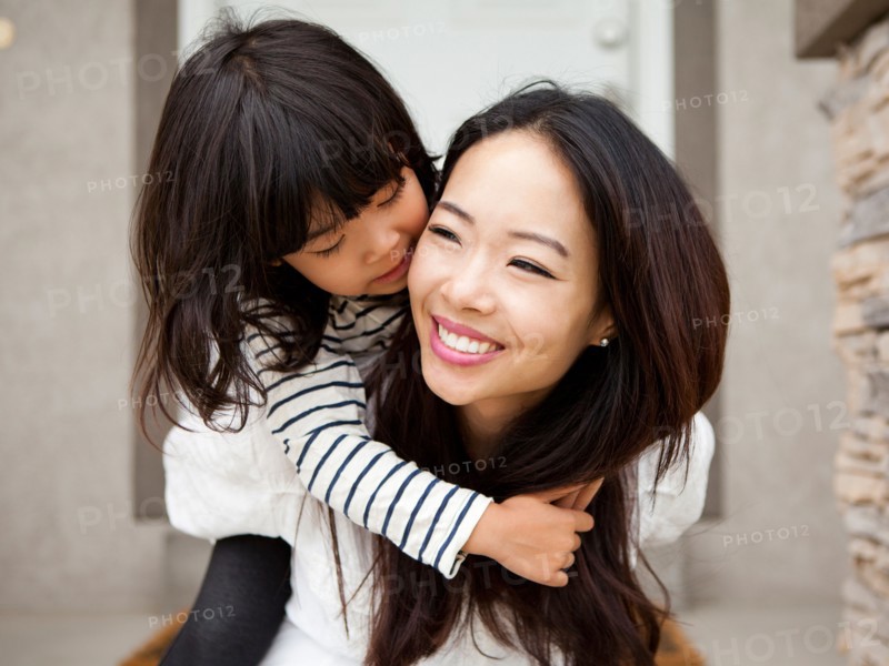 Smiling woman embracing by her daughter (4-5). Photo : Jessica Peterson