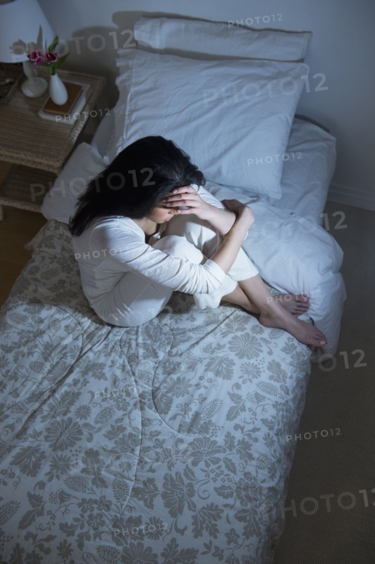Young woman sitting on bed.