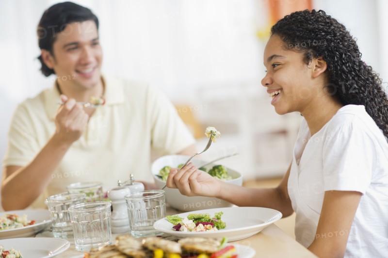 Father with daughter (10-11) eating dinner.