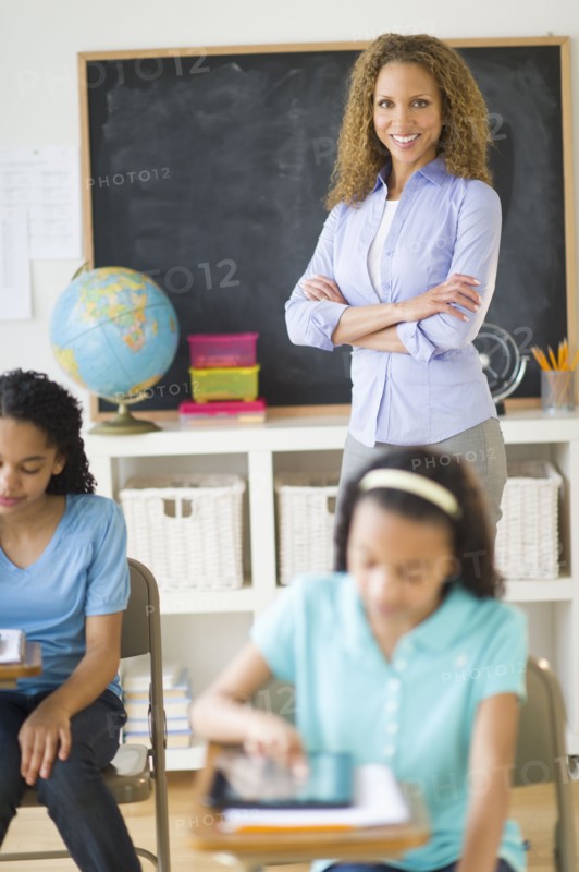Portrait of female teacher in classroom with schoolgirls (10-13).