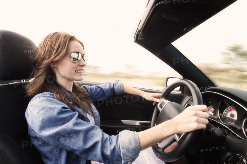 Young woman driving convertible.