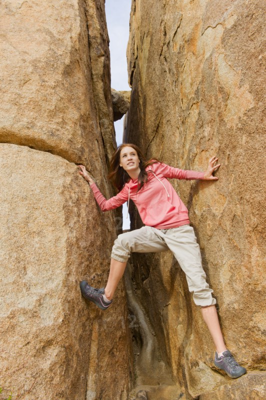 USA, California, Joshua Tree National Park, Young woman climbing canyon walls.
