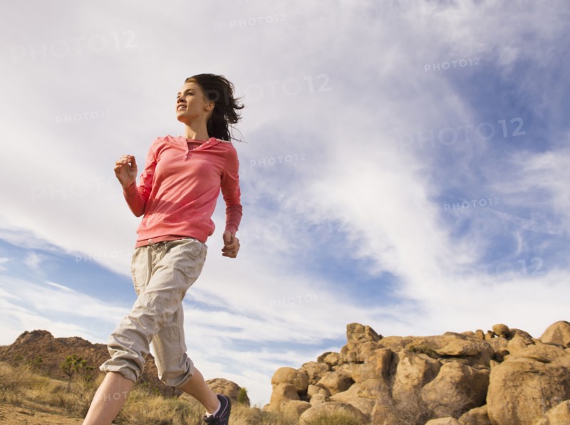 USA, California, Joshua Tree National Park, Young woman jogging in desert.