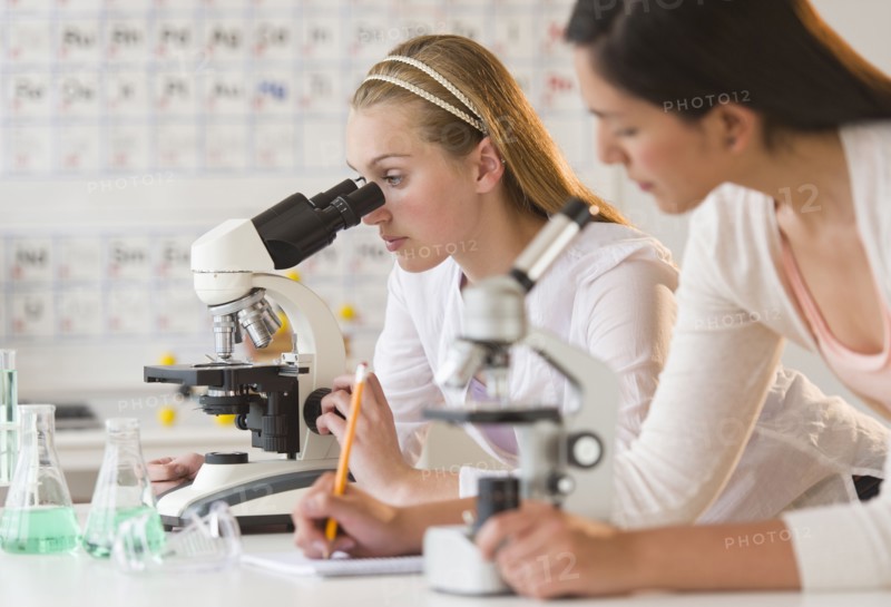 Students (16-19) in chemistry lab using microscope.