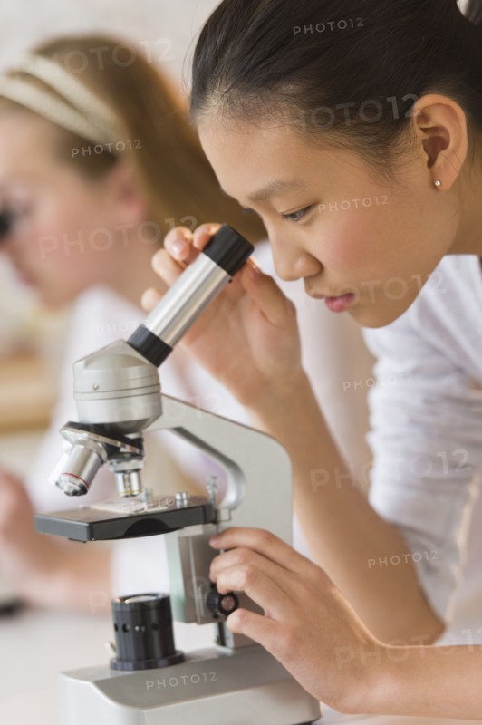 Students (14-17) in chemistry lab using microscope.