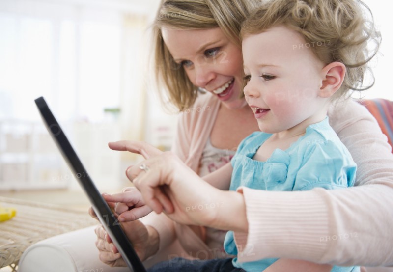 Mother with daughter (-11 months) using digital tablet at home. 
Photo : Jamie Grill