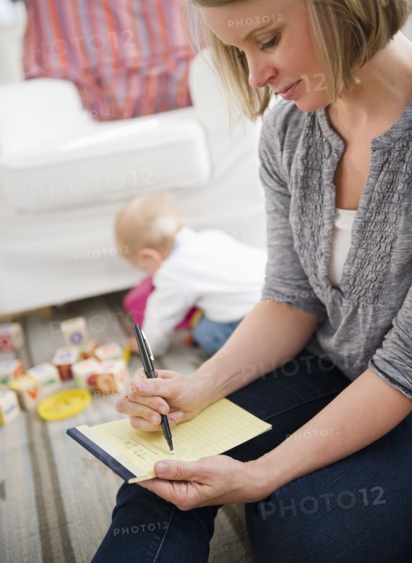 Mother doing notes, son (6-11 months) playing in background. 
Photo : Jamie Grill