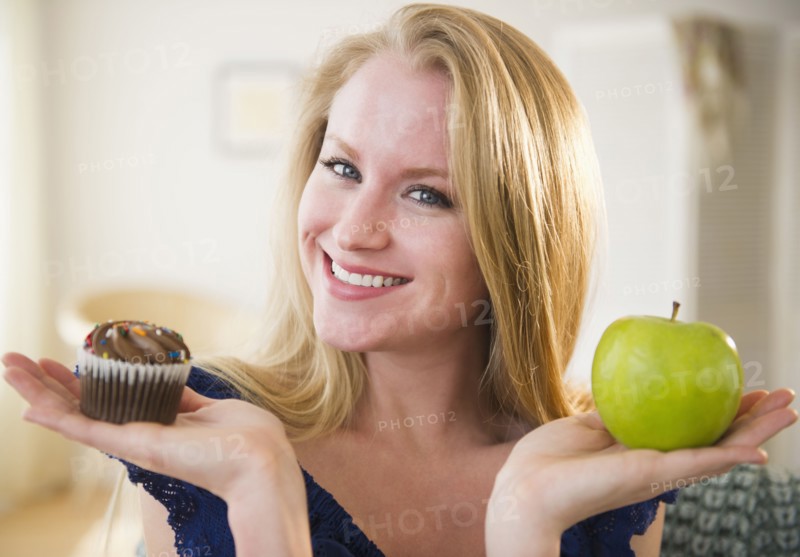 Woman holding apple and cupcake. 
Photo : Jamie Grill