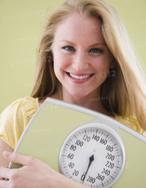 Woman holding bathroom scale. 
Photo : Jamie Grill