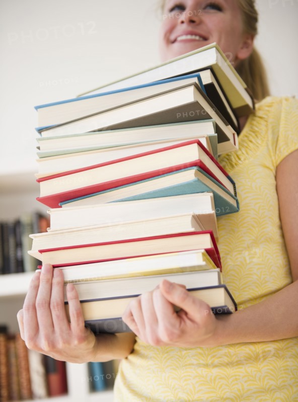 Woman carrying stack of books. 
Photo : Jamie Grill