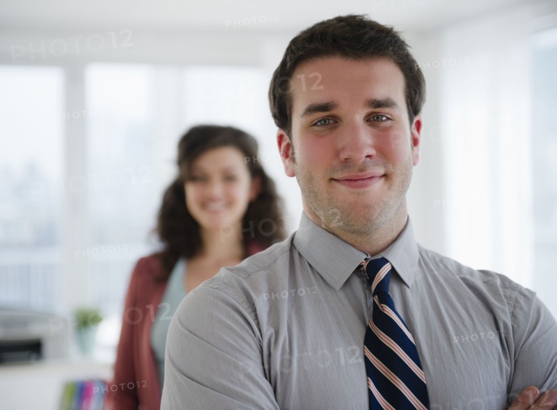 Portrait of business man, business woman in background. 
Photo : Jamie Grill