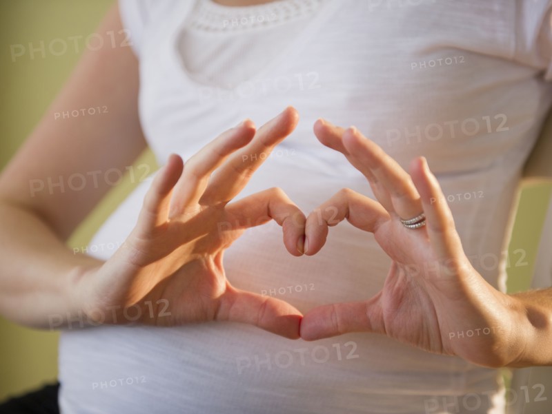 Pregnant woman making heart shape with hands. 
Photo : Jamie Grill