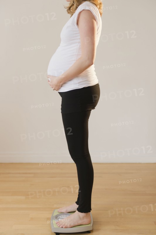 pregnant woman standing on weight scale. 
Photo : Jamie Grill