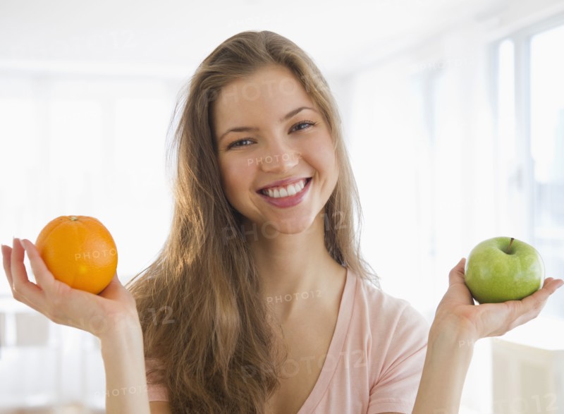 Woman holding orange and apple. 
Photo : Jamie Grill