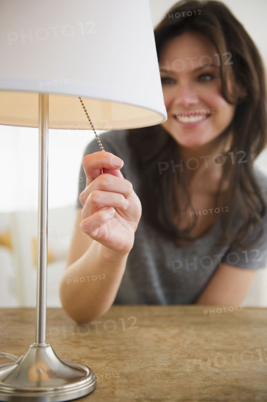 Woman pulling lamp switch. 
Photo: Jamie Grill