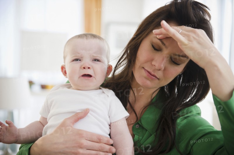 Tired mother holding baby daughter (6-11 months). 
Photo : Jamie Grill